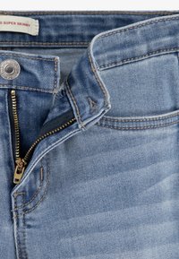 Ljust blå super slim jeans med en gul dragkedja, knappstängning och synliga sömnadsdetaljer. Denimtyg med en mjuk textur.