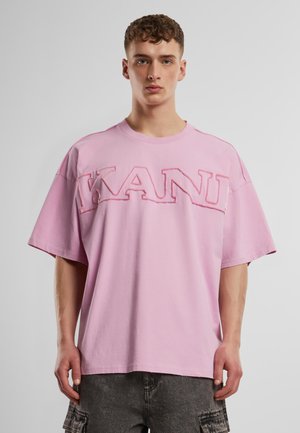 Pink oversized t-shirt with short sleeves, featuring a bold embroidered "KANY" logo on the front. Made from soft cotton, smooth texture.