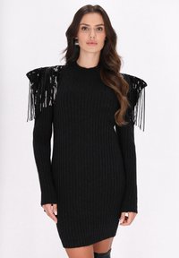 Schwarzes geripptes Strickkleid mit langen Ärmeln, das über Paillettenfransenakzente an den Schultern und eine taillierte Silhouette verfügt.