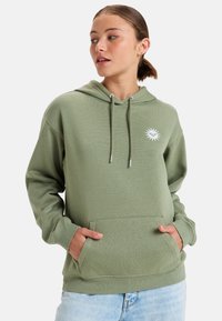 Sudadera verde hecha de tela suave, con un bolsillo frontal, capucha con cordón y un gráfico de sol blanco en el pecho.