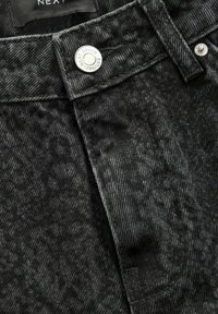 Blugi din denim negru cu un model subtil în herringbone, accesorii argintii la talie și detalii de cusătură distincte.