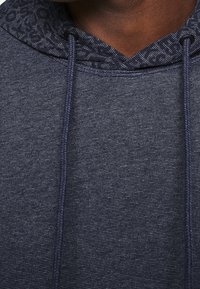 Felpa con cappuccio blu navy con rivestimento interno a motivo blu scuro, dotata di chiusura con lacci e tessuto testurizzato.