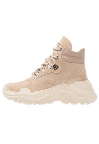 Zapatillas altas de ante beige con suela gruesa crema, con ojales plateados y cierre de cordones; detalles texturizados en la parte superior.