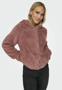 Faux-Fur-Hoodie in staubigem Rosa mit einem Reißverschluss, gerippten Bündchen und Saum. Mit einer verstellbaren Kapuze und seitlichen Taschen. Weiches, strukturiertes Material.