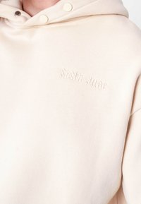 Sudadera color crema con una textura suave, logo bordado "Sixth June" y botones a presión en el cuello. Diseño de corte relajado y suave.
