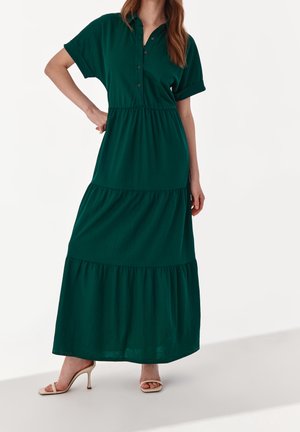 Grünes, kurzärmliges Maxikleid mit Knopfleiste und gestuftem Design. Hergestellt aus weichem Stoff, mit lockerem Schnitt und fließender Silhouette.