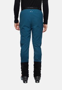 Blauwe skibroek met verstelbare taille, slank design, elastische onderkanten en zwarte accenten. Geschikt voor wintersporten.