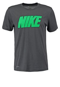 Szara koszulka z krótkim rękawem wykonana z miękkiego materiału, z dużym zielonym logo Nike z przodu. Minimalistyczny design z okrągłym dekoltem.