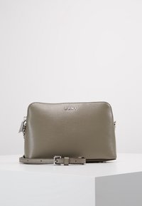 Borsa a tracolla DKNY in morbida pelle grigia con una silhouette rettangolare elegante, tracolla regolabile e un logo discreto in lettering metallico.