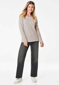 Gestreepte langemouwen top in beige en lichtbruin, gecombineerd met donkergrijze jeans en witte sneakers. Eenvoudig ontwerp met een relaxte fit.