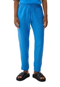 Blå linne joggerbyxor med elastisk midja och framfickor, ihop med svarta sandaler med tjocka korsremmar.