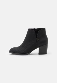 Bottes noires à la cheville avec une finition texturée, dotées d'un panneau élastique pour un enfilage facile et d'un talon épais pour la stabilité. Design à bout rond.