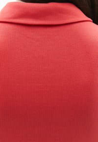 Gestreept rood topje met een omgeslagen kraag, voorzien van een close-up van de textuur die het patroon en de vorm duidelijk benadrukt.