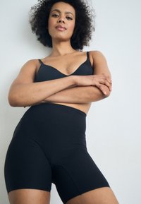 Black seamless high-waisted shorts made of stretchy fabric, hugging thighs, with a smooth texture and no visible seams.
