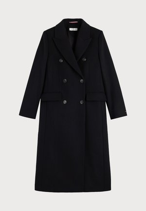 Long manteau noir croisé à larges revers, six boutons, manches longues et poches à rabat, présenté sur un fond uni.