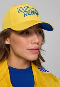 Żółta czapka z niebieskim daszkiem, z wyraźnym niebieskim napisem "Williams Racing" z przodu. Gładki materiał, klasyczny design.