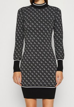 Robe en tricot ajustée noire et blanche à manches longues avec un motif en losange et des manches retroussées, se terminant au-dessus du genou.