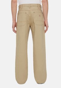 Béžové kalhoty rovného střihu s dvěma zadními kapsami, viditelným kontrastním prošíváním a logem na pravé kapse.