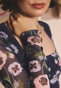 Ilgomis rankovėmis, permatomas gėlių raštų viršus tamsiai mėlyno fono; turi rožinių ir violetinių gėlių raštus, surauktas detales ir kvadratinę iškirptę.