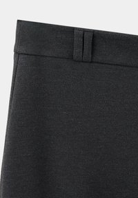 Gros plan sur une ceinture en tissu noir avec des passants de ceinture sur un pantalon ou une jupe sur mesure.