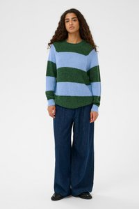 Pull à rayures bleu clair et vert foncé, en tricot texturé ; associé à un pantalon en denim large et des chaussures noires.