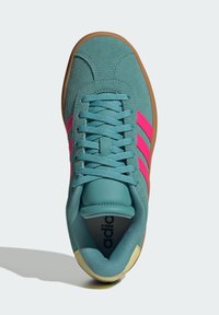 Sneaker in suede verde acqua con strisce rosa, punta rotonda, chiusura con lacci e suola in gomma naturale. L'interno presenta una linguetta imbottita e il marchio.