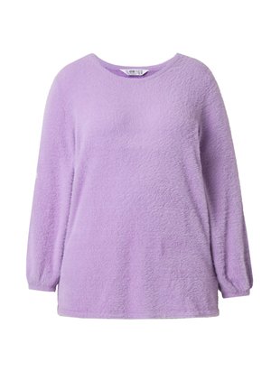 Pehmeä, pitkähiha laventelinvärinen neulepyjama jossa pyöreä pääntie ja hieman kerätyt hihansuut, valmistettu pörröisestä tekstuurikankaasta.