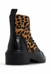 Stivaletto in pelle nera con pannello in tessuto leopardato, punta arrotondata, tacco basso e design con lacci neri. Superficie testurizzata sulla sezione leopardata.