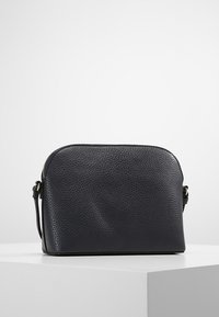 Sort læder crossover taske med struktureret overflade, rund top og hardware i guldtoner. Kompakt design, der er velegnet til daglig brug.