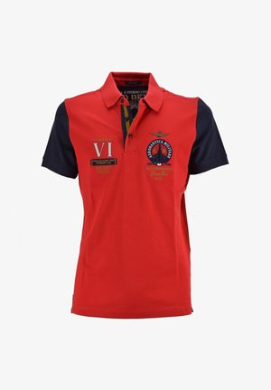 Polo rosso con maniche blu navy, dotato di loghi militari ricamati e dettagli, colletto e bottoni sulla parte anteriore. Materiale in cotone.