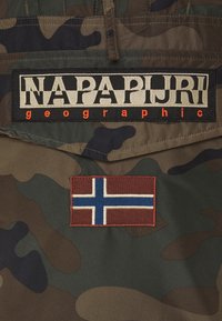 Kamuflage-stof med rektangulært "Napapijri geographic" logo-patch over et rød, hvid og blåt Nordisk kors flag-patch.