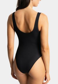 Maillot de bain une pièce noir à côtes avec de larges bretelles et un dos décolleté, présentant une jambe haute et un tissu lisse et extensible.