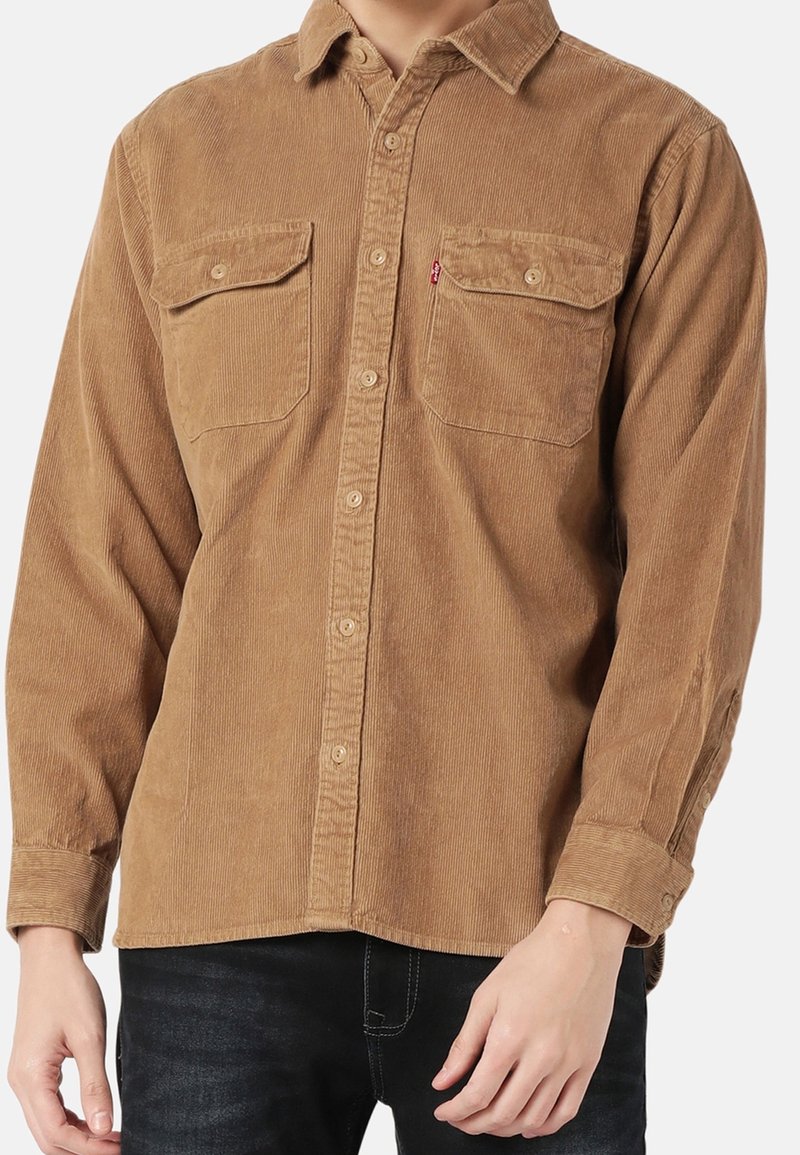 Bruine corduroy blouse met lange mouwen, twee borstzakken en een knoopsluiting aan de voorkant. Kenmerkt zich door een gestructureerde stof en een getailleerde pasvorm.
