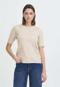 T-shirt beige à manches courtes avec un col rond, en mélange de coton doux. Doté d'une coupe décontractée et d'un design minimaliste, associé à un jean en denim bleu.