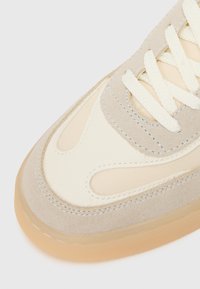 Beige sneakers med en glatt semsket og mesh-overdel, med en kremfarget tåboks og ton-i-ton sømmer, fullført med en gjennomsiktig gummisåle.