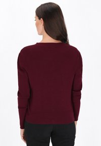 Bordowy sweter prążkowany z długimi rękawami, okrągłym dekoltem i dopasowanym krojem. Tkanina wydaje się miękka z lekkim rozciągliwością.