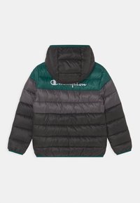 Doudoune, avec un mélange de noir et de vert. Le dos présente des sections matelassées horizontales et un grand logo "Champion" sur les épaules.