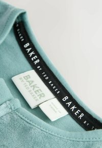 T-shirt azzurro chiaro con colletto rotondo, caratterizzato da un'etichetta nera con la scritta "BAKER by TED BAKER" e etichette di cura in bianco. Texture morbida.