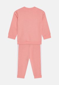 Set de hanorac roz și pantaloni de trening asortați. Material din bumbac, manșete cu nervuri și dungi albe pe pantaloni. Vedere din spate, design simplu.