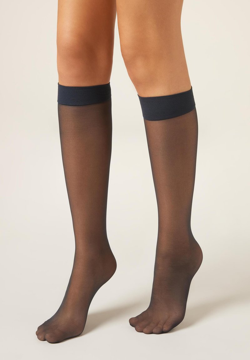 Černé průsvitné podkolenky s tmavě modrým pevným pruhem nahoře. Otevřená špička. Hladká textura, lehký materiál.