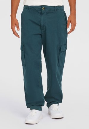 Teal cargo bukser lavet af letvægtstof, med sidelommer, knaplukning og afslappet pasform. Båret med hvide sneakers.
