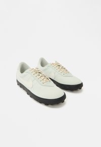 Αθλητικά παπούτσια σε ανοιχτό μέντα πράσινο με λείο επάνω μέρος, μπεζ κορδόνια και μαύρη ελαστική σόλα με υφή και προεξοχές για καλύτερη πρόσφυση.