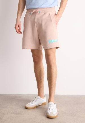 Helle rosa Shorts mit einem Kordelzugbund, Seitentaschen und einem blauen Grafikdruck am linken Bein. Weicher Stoff und lässige Passform.