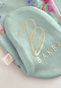 Meki tirkizni kuhinjski rukavac s cvjetnim uzorkom, s zlatnim logotipom "PB BAKER." Glatka tekstura s tekstilnom oznakom sa strane.