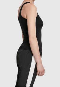 Débardeur noir ajusté avec un col rond et des bretelles larges, fabriqué en coton lisse. Présente un design sans couture et sans accents visibles.