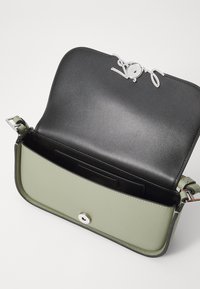 Borsa a tracolla in pelle verde e nera con chiusura a logo in argento, caratterizzata da un esterno liscio e una tasca interna contraddistinta da una texture.