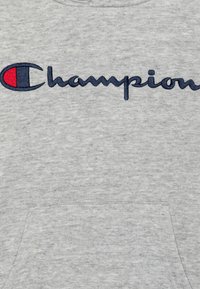Felpa grigia in cotone con grande logo ricamato "Champion". Il design include un accento rosso e blu all'interno del logo. Taglio orizzontale.