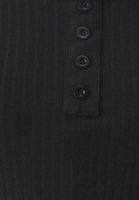 Tessuto a costine nero con design a colletto, caratterizzato da una patta con cinque bottoni neri. Superficie textured con strisce verticali.