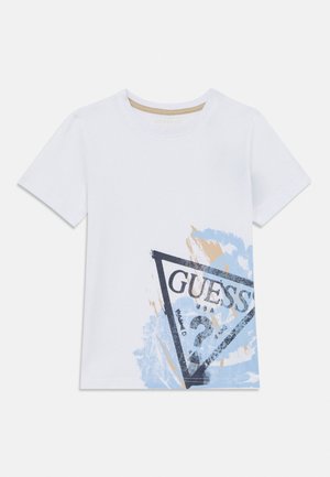 T-shirt bianca a maniche corte con un grande motivo a pennellate sbiadite blu e beige e un logo triangolare nero "GUESS ?" sul davanti.