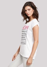 Weißes Baumwoll-T-Shirt mit umgeschlagenen Ärmeln, das pinken und schwarzen Text trägt. Gerade geschnittenes Design, weiche Textur, geeignet für lässige Outfits.